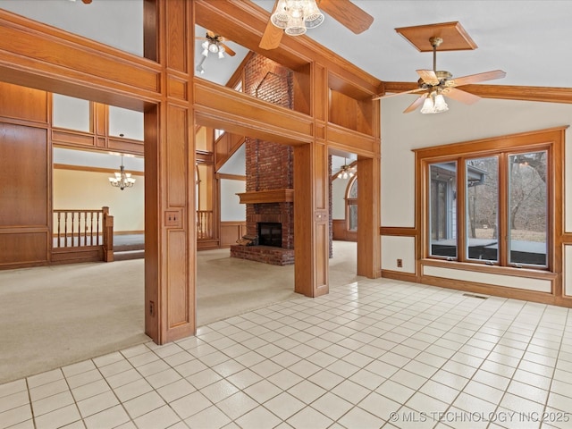 unfurnished living room with light tile patterned floors, light carpet, a fireplace, and ceiling fan with notable chandelier