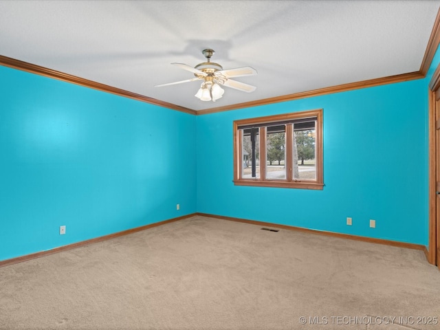 carpeted spare room with ceiling fan, baseboards, visible vents, and ornamental molding