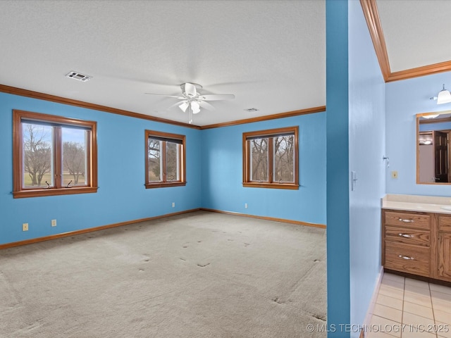 unfurnished bedroom featuring light carpet, visible vents, baseboards, and ornamental molding