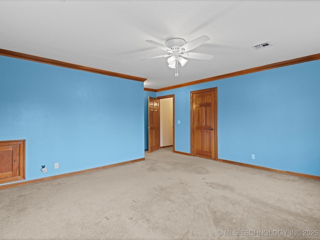 carpeted spare room featuring crown molding, baseboards, visible vents, and ceiling fan