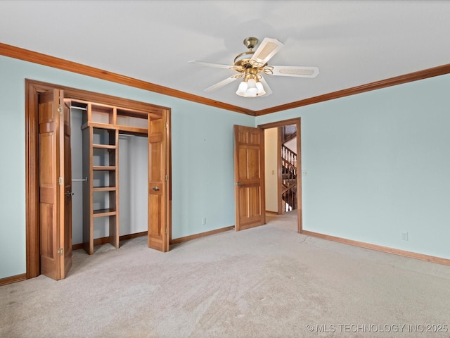 unfurnished bedroom with baseboards, ceiling fan, a closet, crown molding, and carpet flooring