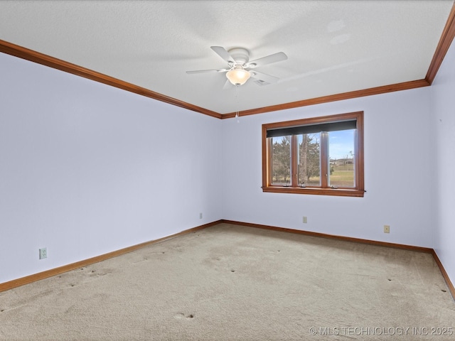 carpeted spare room featuring a ceiling fan, baseboards, and ornamental molding