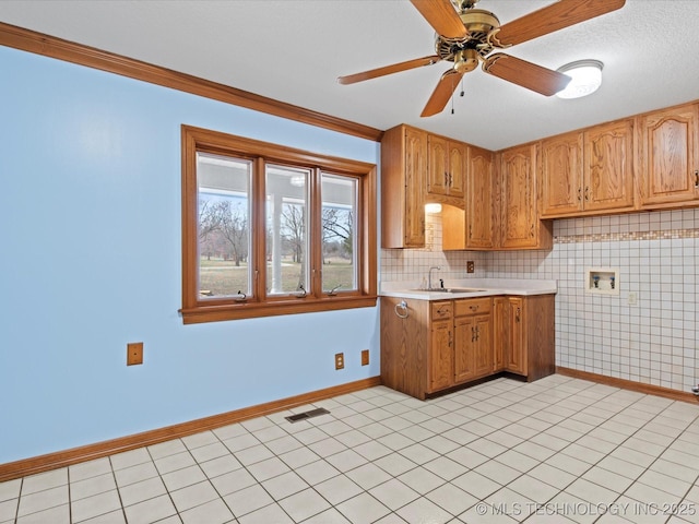 kitchen with visible vents, light countertops, baseboards, and a sink