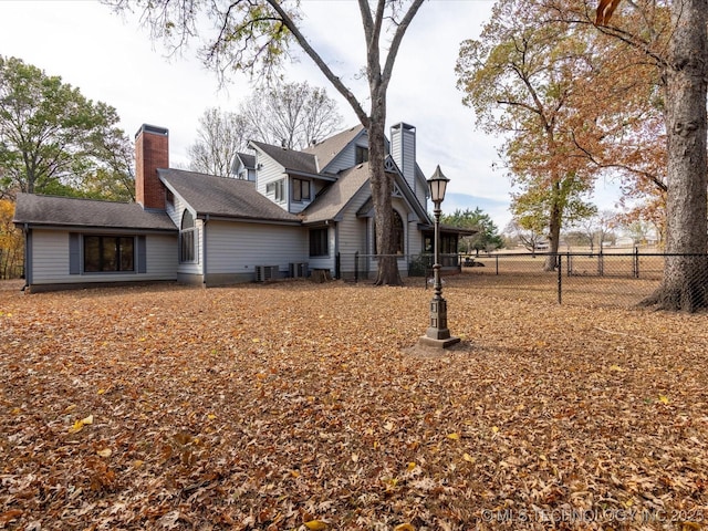 back of house with a chimney and fence