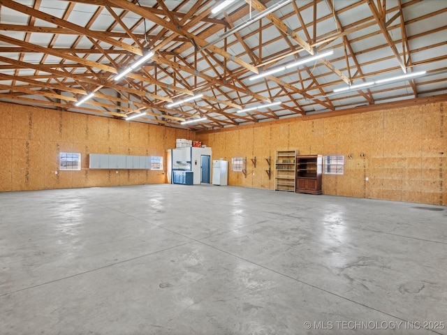 garage with white refrigerator with ice dispenser and freestanding refrigerator