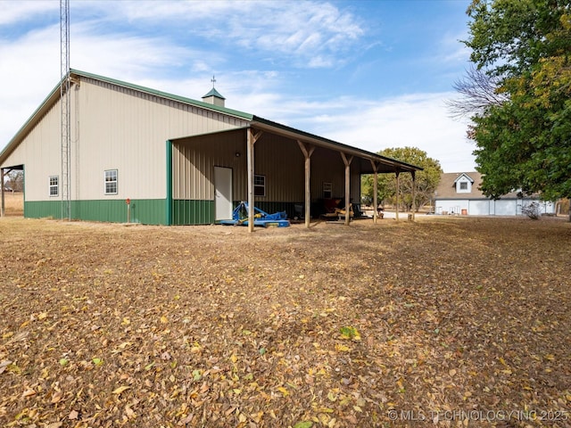 rear view of house featuring an outdoor structure, a garage, and a pole building