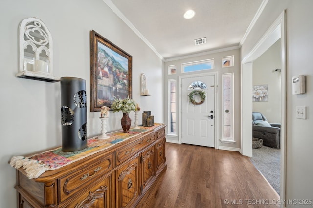 entryway with dark wood finished floors, baseboards, visible vents, and ornamental molding