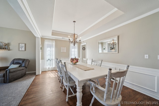 dining space with a wainscoted wall, a raised ceiling, dark wood-type flooring, and crown molding