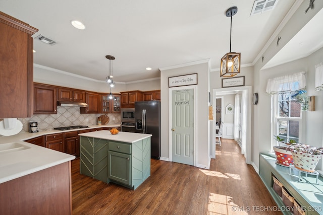 kitchen featuring visible vents, under cabinet range hood, appliances with stainless steel finishes, light countertops, and decorative backsplash