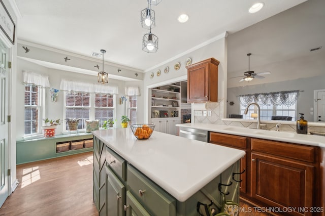 kitchen featuring light wood finished floors, a sink, light countertops, pendant lighting, and dishwasher