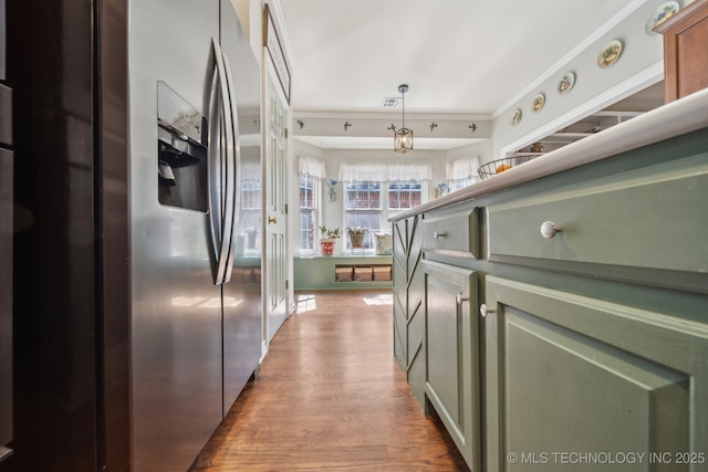 kitchen with decorative light fixtures, wood finished floors, stainless steel refrigerator with ice dispenser, and ornamental molding