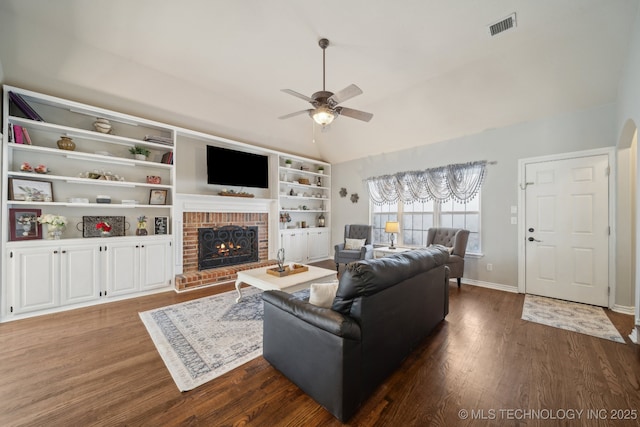 living room with dark wood finished floors, lofted ceiling, a brick fireplace, and visible vents