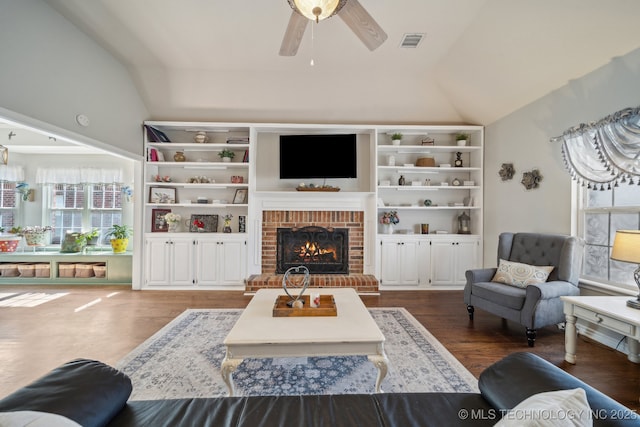 living room featuring wood finished floors, visible vents, lofted ceiling, a fireplace, and ceiling fan