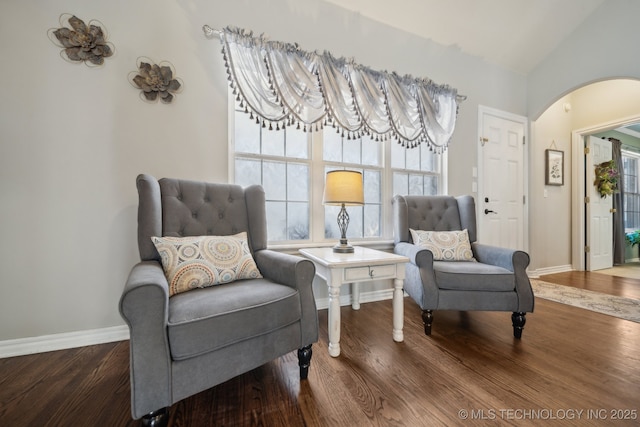 living area with arched walkways, lofted ceiling, baseboards, and wood finished floors