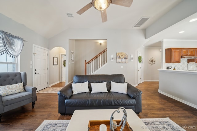 living area with dark wood finished floors, arched walkways, and visible vents