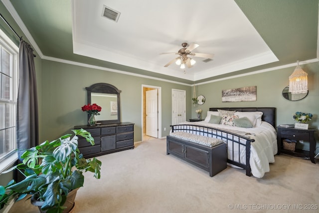 bedroom featuring a tray ceiling, crown molding, light colored carpet, and visible vents