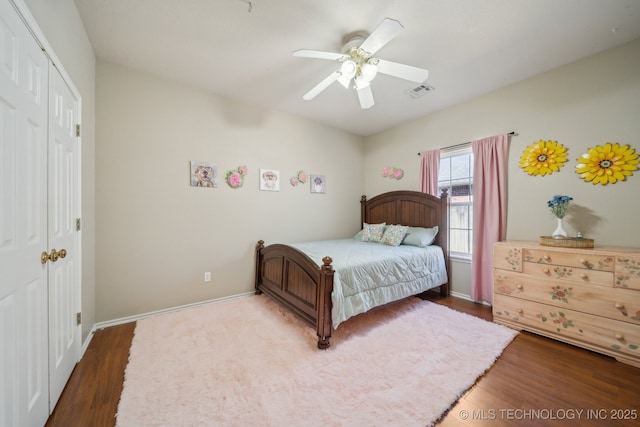 bedroom featuring visible vents, wood finished floors, a closet, baseboards, and ceiling fan