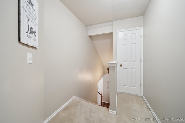 interior space with an upstairs landing, baseboards, and carpet