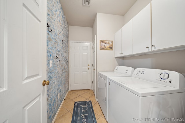 laundry area featuring visible vents, wallpapered walls, washer and clothes dryer, light tile patterned floors, and cabinet space