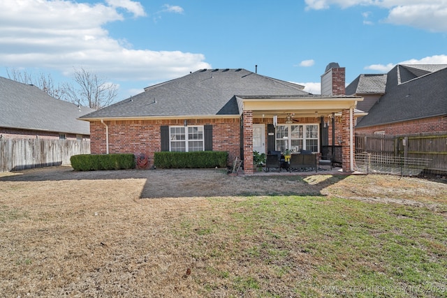 rear view of house with brick siding, a lawn, and ceiling fan