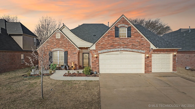 traditional home featuring brick siding, a shingled roof, a front lawn, a garage, and driveway