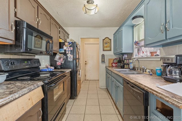 kitchen with light tile patterned floors, a sink, decorative backsplash, black appliances, and blue cabinets