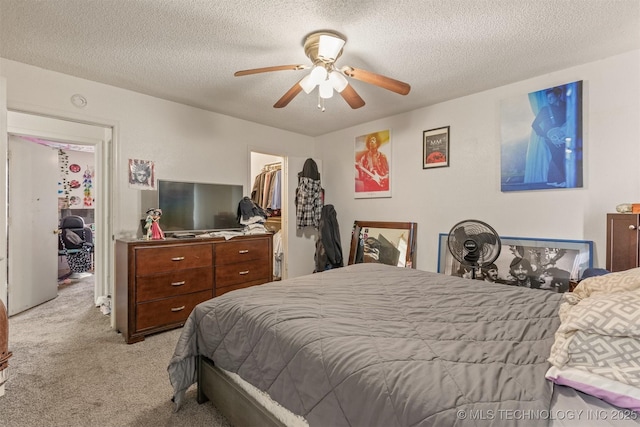 bedroom with ceiling fan, a spacious closet, a closet, a textured ceiling, and light colored carpet