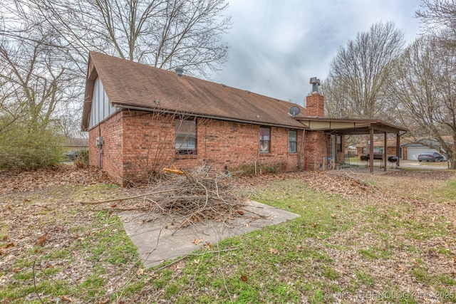 back of house featuring brick siding, a chimney, and roof with shingles