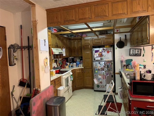 kitchen featuring under cabinet range hood, white range with electric stovetop, freestanding refrigerator, light countertops, and light floors