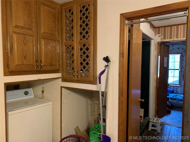 clothes washing area with wood finished floors, washer / clothes dryer, and cabinet space