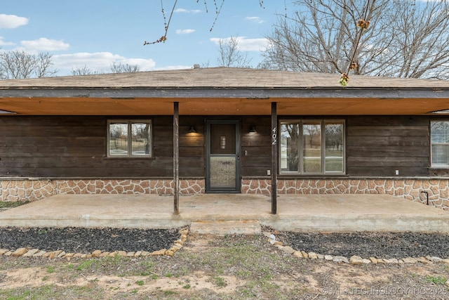 doorway to property with a shingled roof