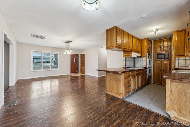 kitchen with visible vents, backsplash, stainless steel appliances, and wood finished floors