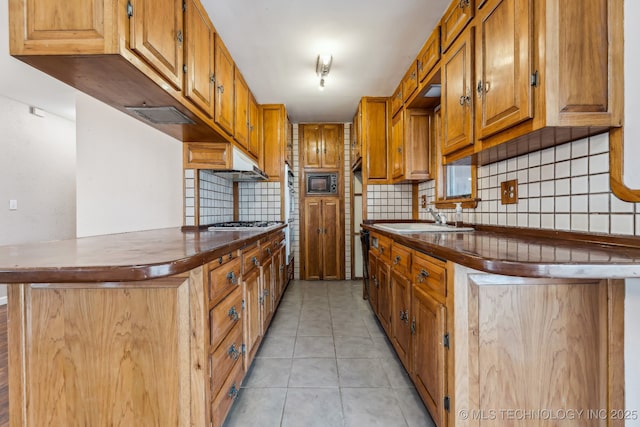 kitchen with a sink, dark countertops, black microwave, light tile patterned floors, and decorative backsplash