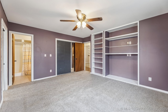 unfurnished bedroom featuring ensuite bath, carpet, baseboards, and ceiling fan