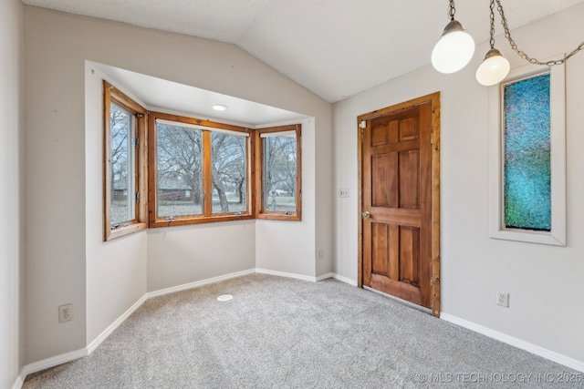 carpeted foyer entrance featuring vaulted ceiling and baseboards