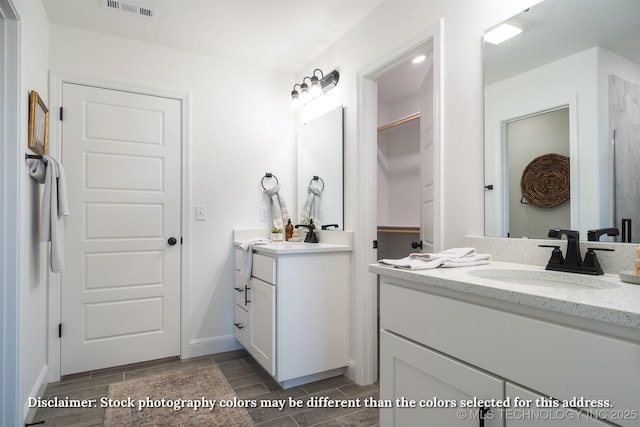 bathroom featuring visible vents, wood finish floors, a sink, and two vanities