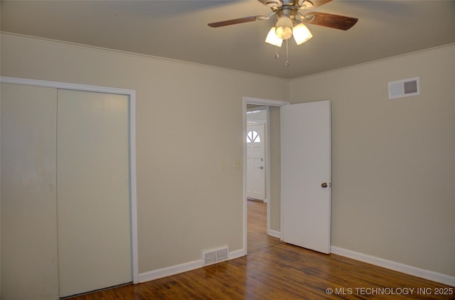 unfurnished bedroom featuring visible vents, baseboards, wood finished floors, and ornamental molding