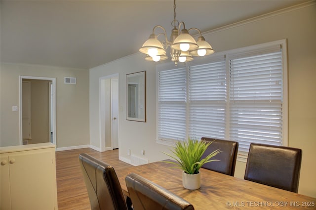 dining room featuring visible vents, baseboards, ornamental molding, wood finished floors, and a notable chandelier