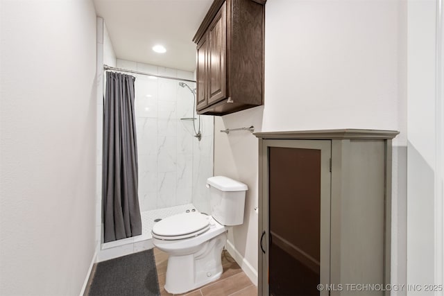 bathroom with toilet, a stall shower, and baseboards
