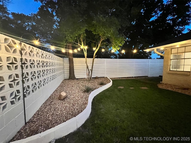 yard at twilight featuring a fenced backyard