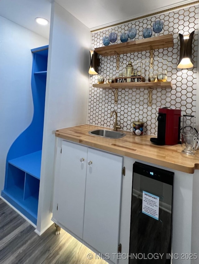 bar with wine cooler, backsplash, wood finished floors, and a sink