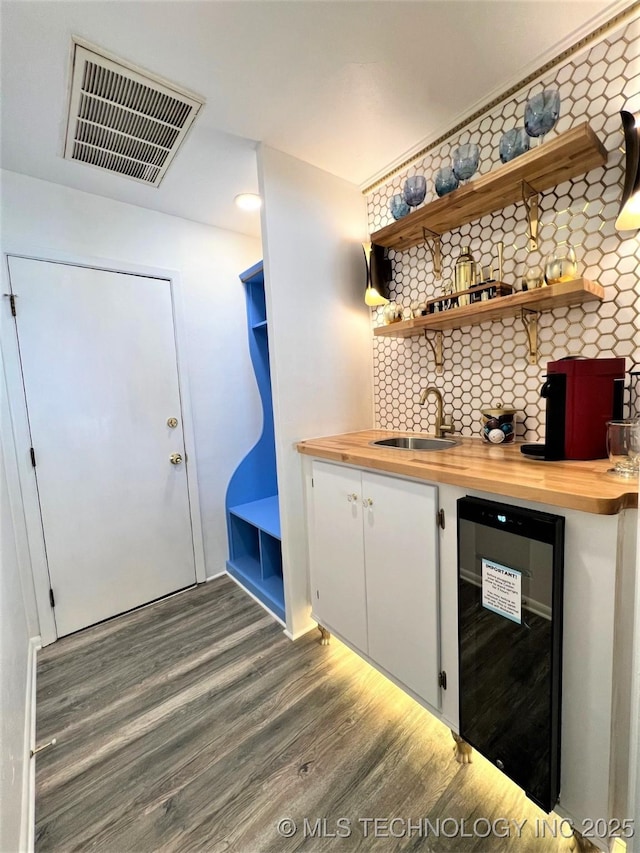 bar with visible vents, a sink, backsplash, wood finished floors, and wine cooler