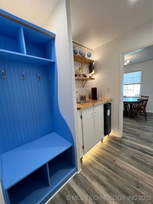 mudroom featuring dark wood finished floors, wine cooler, a dry bar, and a sink