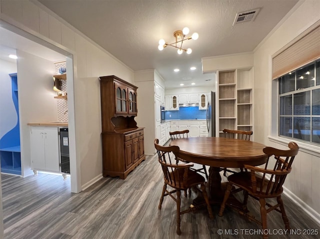 dining room with visible vents, crown molding, an inviting chandelier, and wood finished floors