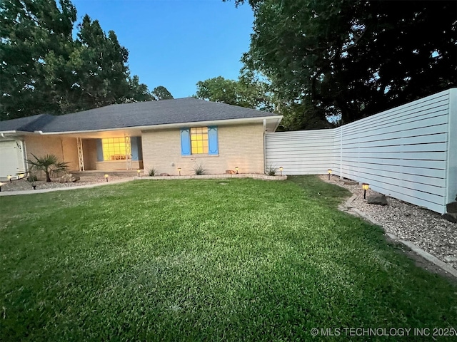 view of front of property featuring a front yard, fence, and brick siding