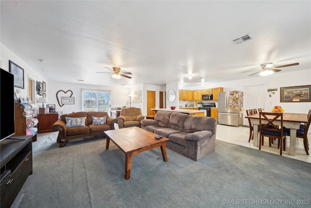 living room with visible vents, light carpet, and a ceiling fan