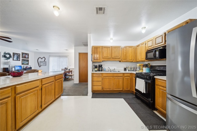 kitchen featuring visible vents, a sink, black appliances, light countertops, and open floor plan