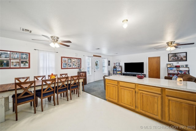 kitchen with visible vents, open floor plan, light countertops, brown cabinetry, and a ceiling fan