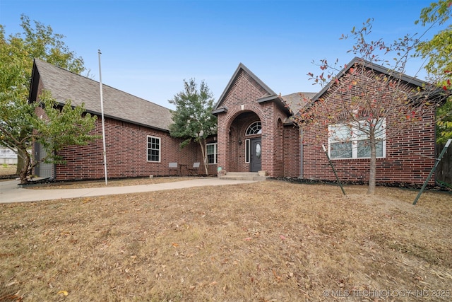 view of front of home with brick siding and roof with shingles