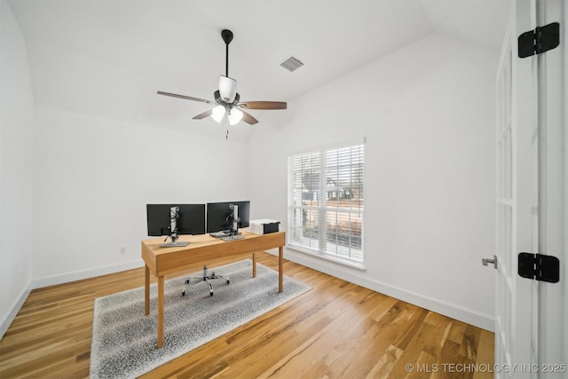 office space featuring a ceiling fan, baseboards, visible vents, light wood finished floors, and vaulted ceiling